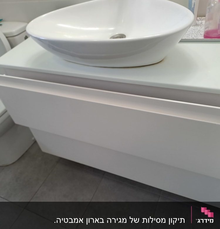 ארון אמבטיה עם מגירה פתוחה וכיור עליון